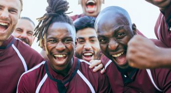 a group of male athletes cheer at the camera